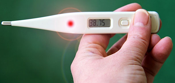 A hand holding a thermometer with a reading of 38.75 